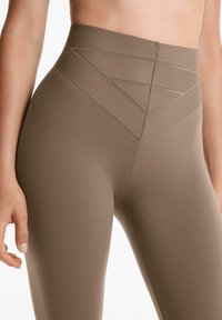 Hoogwezellige bruine leggings met ribbelaccenten en een gladde textuur. Ontworpen voor comfort met een contourede pasvorm.