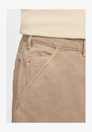 Beige Baumwollhosen mit glatter Textur, schrägen Fronttaschen und sichtbaren Nähten entlang der Nähte.