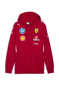 Sarkana kapuce ar kokauduma maisījumu. Iespējas ar baltām akcentiem, kangaroo kabatu un vairākiem logotipiem: Ferrari, HP, Shell, UniCredit.