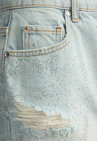 Pantalones cortos de mezclilla de color azul claro con adornos de rhinestones, bordes deshilachados y un diseño clásico de cinco bolsillos.