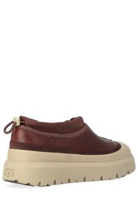 Sneaker marrone in pelle con tomaia testurizzata, suola in gomma beige spessa e linguetta posteriore per indossarla facilmente.