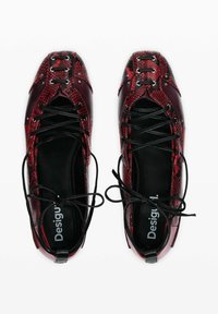 Rode en zwarte slangenprint schoenen met een glanzende leren afwerking, frontale vetersluiting en contrasterende zwarte veters.