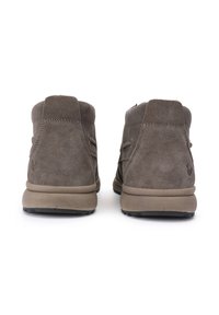 Botas de ante marrón hasta el tobillo con cuello acolchado, punta redonda y suela de goma. Presentan acentos cosidos y un logo sutil en el tacón.