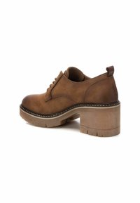 Zapato de cuero marrón con puntera redonda, diseño de cordones y una suela gruesa, texturizada y transparente. Tiene un taco bajo.