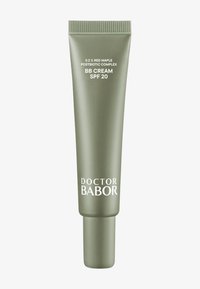 Tubo verde de crema BB con SPF 20. Presenta un acabado mate, forma cilíndrica y texto impreso en blanco que indica los detalles del producto y la marca.