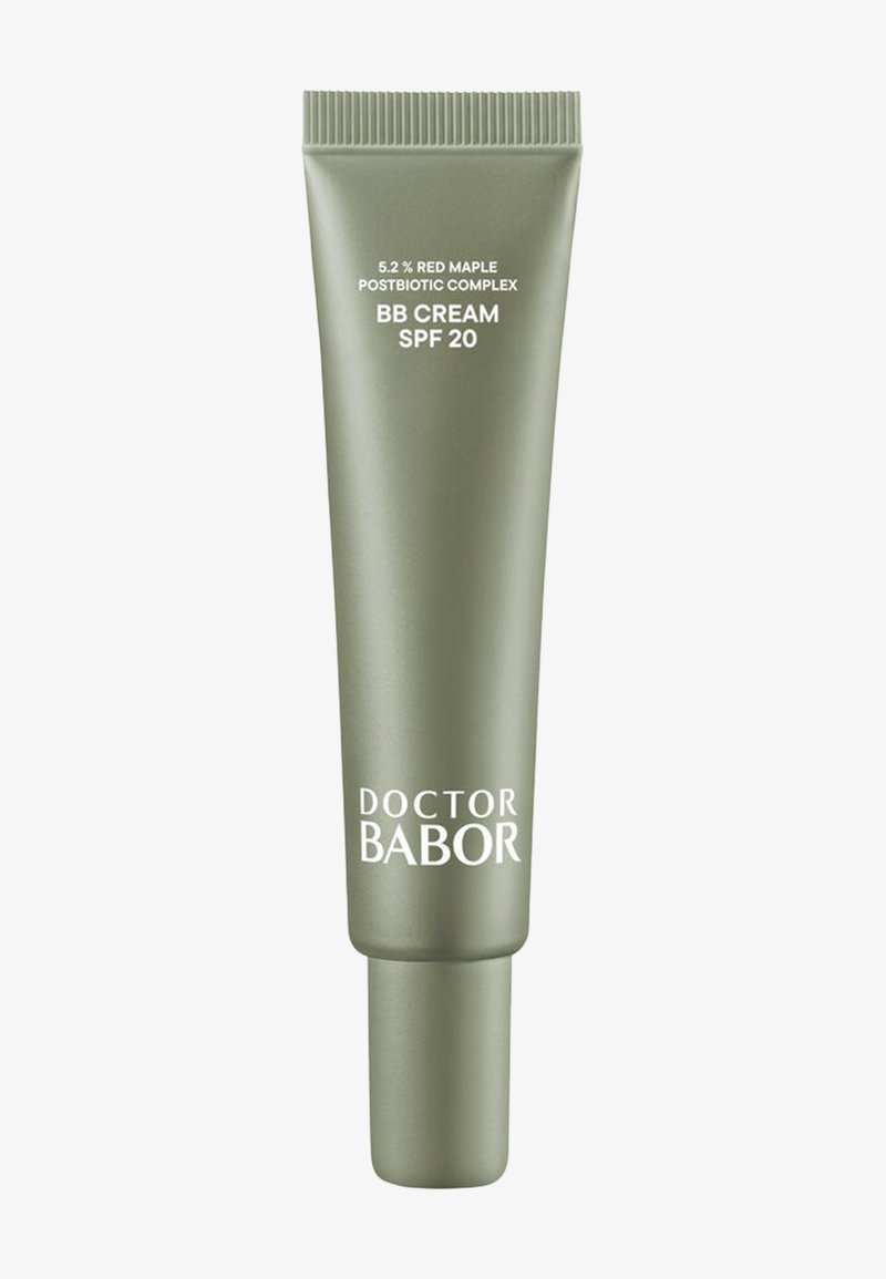 Tubo verde de crema BB con SPF 20. Presenta un acabado mate, forma cilíndrica y texto impreso en blanco que indica los detalles del producto y la marca.