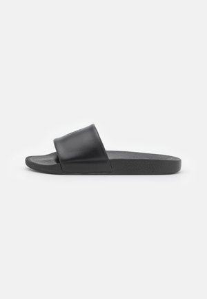 Schwarze Slidesandale mit breitem Riemen und strukturierter Sohle, aus der Seitenansicht auf weißem Hintergrund dargestellt.