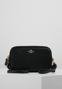 Mustakiminen nahkainen olkalaukku, jossa on rakenneviimeistely, kultaiset varusteet, vetoketjukiinnitys ja säädettävä hihna. Kompakti suorakaiteen muotoinen.