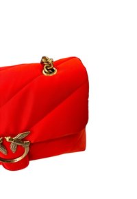 Borsa a tracolla in nylon trapuntato rosso con hardware dorato, caratterizzata da un motivo di uccello e una tracolla a catena. Il design include cuciture diagonali e bordi arrotondati.