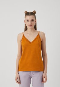 Sennepsgul tank topp med bølget hals og justerbare stropper, laget av lett stoff. Kombinert med lyse lilla bukser.