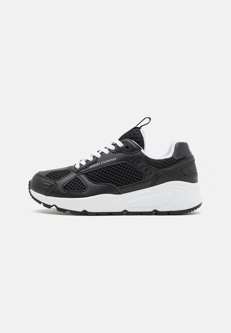 Black and white mesh sneakers with a textured black leather upper, rubber outsole, and white laces. Features a back pull tab for easy wear.