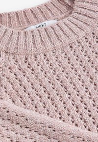 Sweter robiony na drutach w jasnym różu z teksturowanym wzorem i cekinowymi akcentami. Posiada prążkowany okrągły dekolt i miękki materiał. Widoczna metka marki.