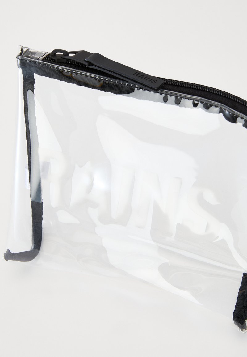 Transparante plastic zak met een zwarte ritssluiting, featuring een reliëf "RAINS" logo, rechthoekige vorm, gladde oppervlakte en geen zichtbare patronen.