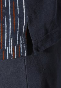 Navy-Shirt aus strukturiertem Stoff mit vertikalen Streifen in Weiß und Orange. Mit einer seitlichen Schlitzeinfassung am Saum.