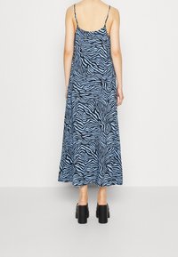Maxi šaty v modré barvě s černými zebřími pruhy, s tenkými ramínky a uvolněným střihem, který sahá do poloviny telat. Vyrobeno z lehkého materiálu.