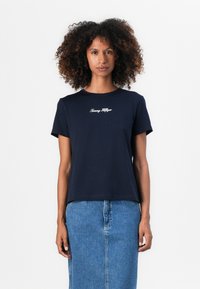 Námořnická modrá bavlněná tričko s krátkými rukávy, s bílou vyšívanou „Tommy Hilfiger“ logem na hrudi. Casual střih.