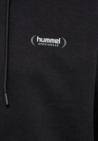 Zwart sportkledingstof met een grijs "hummel SPORTSWEAR" logo gedrukt bij een zwart trekkoord.