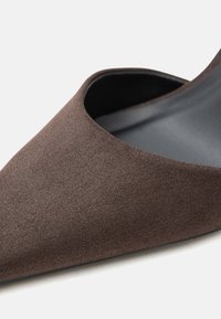 Καφέ σουέντ επίπεδο παπούτσι με μυτερή μύτη, σχεδιασμό slip-on και λεία εσωτερική επένδυση.