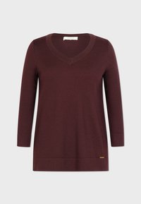 Burgunderfarbener V-Ausschnitt-Pullover aus weichem Strickstoff, mit langen Ärmeln und einem dezenten Logoakzent am Saum. Glatte Textur und lässige Passform.