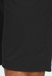 Black shorts made of a smooth, lightweight fabric. Features a straight cut with a stitched hem and no visible patterns or hardware.