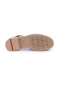 Suola in gomma beige con motivo di presa testurizzato, caratterizzata da un leggero tacco e un accento rosso vicino alla parte posteriore. Branding minimale evidente.