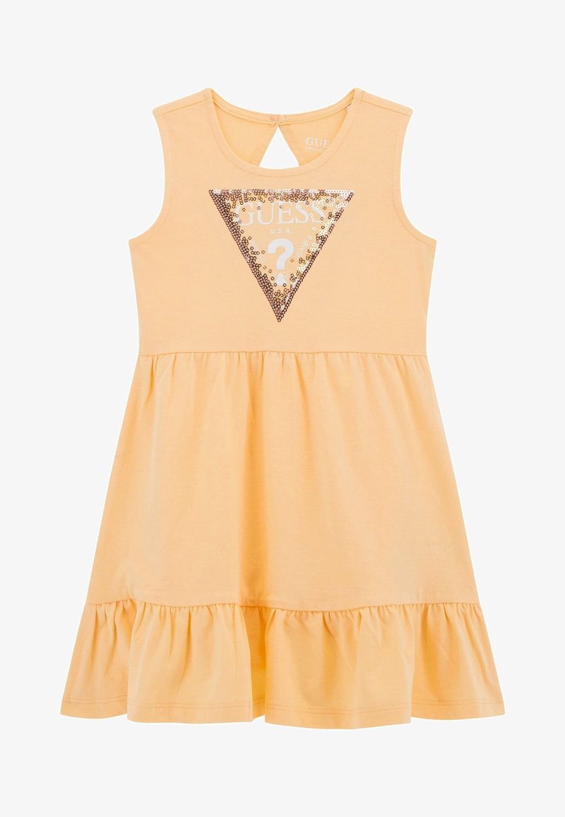 Robe sans manches orange clair avec ourlet à volants, triangle avec logo GUESS orné de sequins sur la poitrine, et fermeture à bouton avec ouverture en forme de goutte à l'arrière du col.