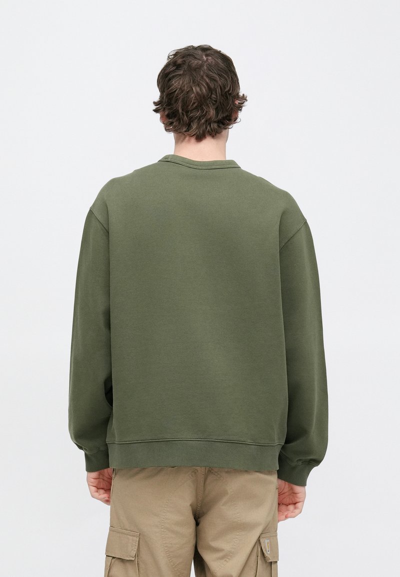 Olive green sweatshirt with long sleeves, ribbed cuffs, and crew neckline. Soft fabric with a relaxed fit, styled without visible branding.