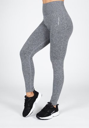 Grijze high-waisted leggings in een gestructureerde, gemêleerde stof met contrasterende naden. Gecombineerd met zwarte sportieve schoenen.