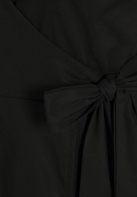 Černé zavinovací šaty s detailem předního uzlu, hladkou texturou a jemnou tkaninou. Design zahrnuje výstřih do V a volnou siluetu.