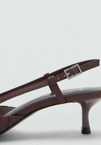 Ruskeat slingback-korkokengät kiiltävällä pinnalla, joissa on ohut hihna ja neliömuotoinen strassisolki. Tyylikäs, teräväkärkinen muotoilu.