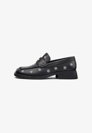Mocasines de cuero negro con bordado de estrella floral plateada, punta redondeada y tacón cuadrado para mayor altura y estabilidad.