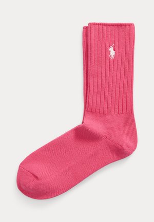 Helelellisinine soonikuga sokk, millel on valge kirjatud polo mängija logo manseti lähedal, asetatud lamedalt heledale taustale.