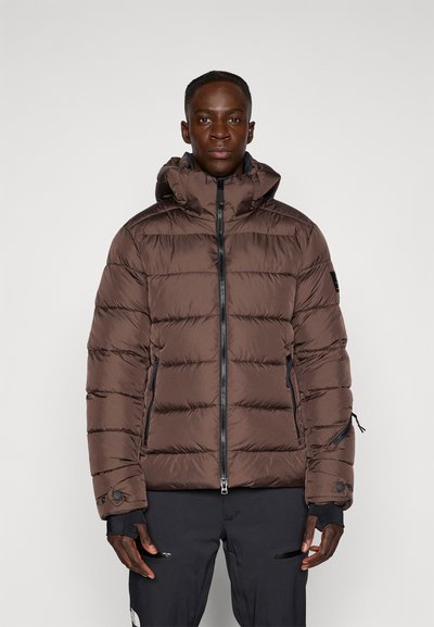 Veste en duvet marron avec capuche, présentant des panneaux matelassés horizontaux, une fermeture à glissière à l'avant et des poches latérales. Fabriquée à partir d'un matériau léger et brillant.