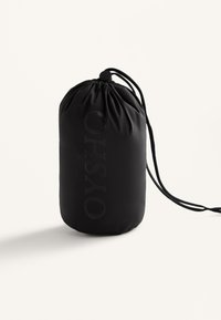 Zwarte trekzak gemaakt van een gladde stof, met het reliëf brandlogo "OYSHO" aan de voorkant, cilindervormig en met een verzameld bovenstuk.