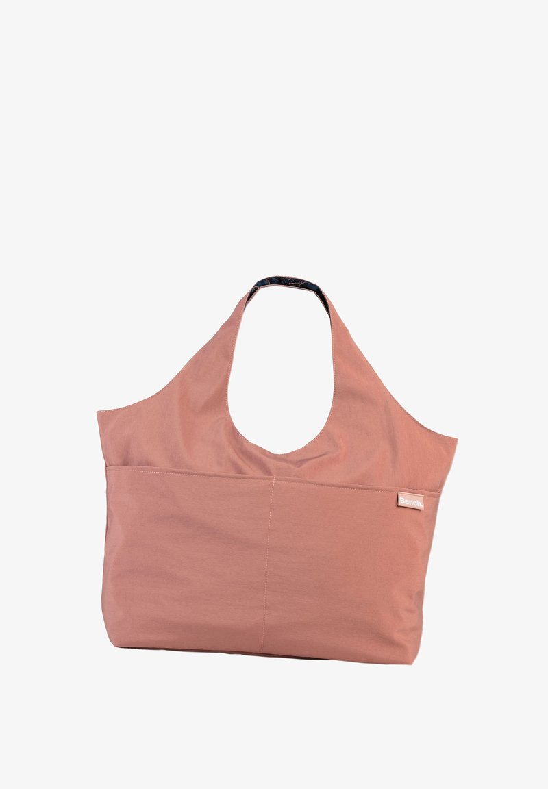 Roze stoffen draagtasje met een breed, open ontwerp en een enkele schouderband. Voorzien van een voorvak en een donkergestreepte voering.