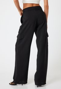 Zwarte cargobroek met een relaxed fit, met zijzakken, een gestructureerde stof en een hoge tailleband. Glad afgewerkte naden en een rechte pijpdesign.