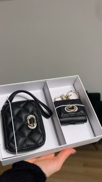 Zwart leren accessoireset met een doorgestikte kaarthouder met een zilverkleurig metalen detail en een kleinere sleutelhangerhouder, beide in een geschenkdoos.