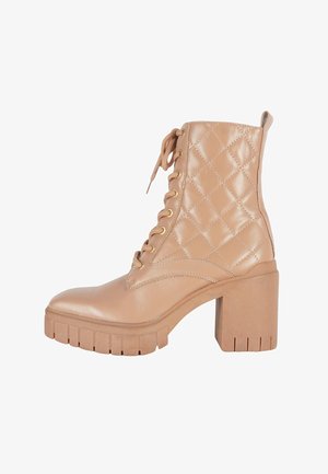 Stivaletto alla caviglia in pelle trapuntata color tan con tacco largo a blocco, allacciatura frontale con occhielli in metallo e suola scanalata.