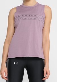 Ljuslila ärmlös träningslinne med rundhals, med svart horisontell text "UNDER ARMOUR". Mjukt, slätt tyg.