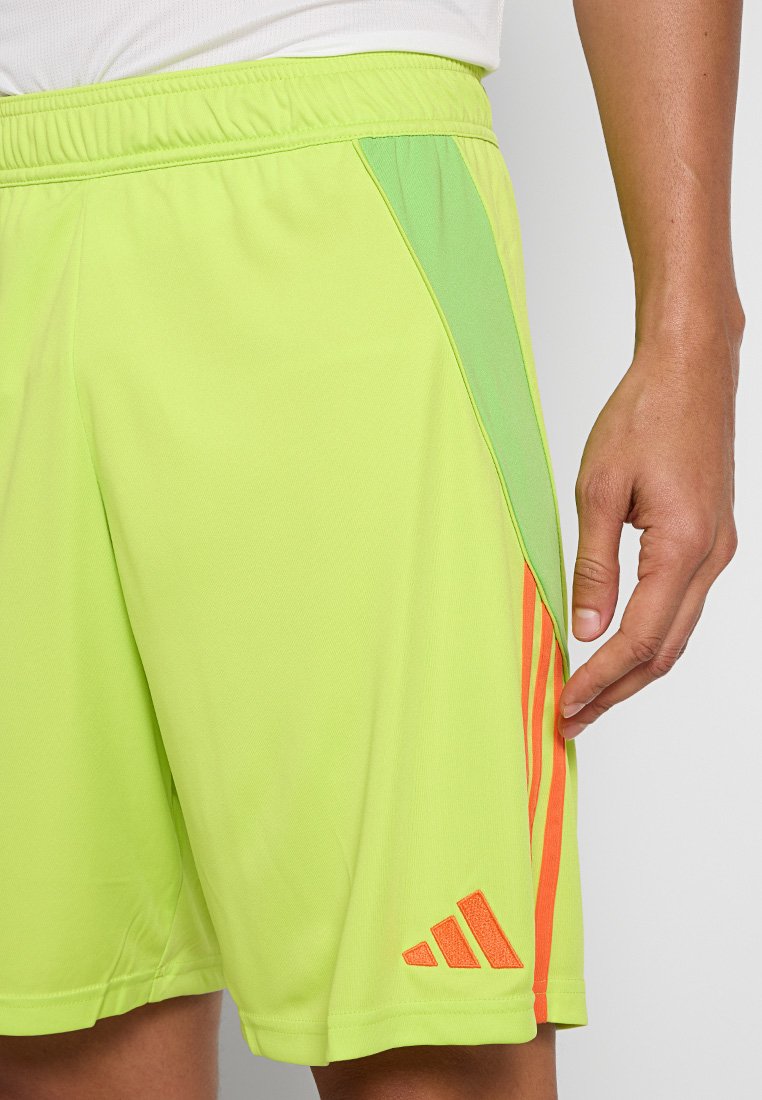 Shorts de sport vert lime en tissu léger, avec des panneaux latéraux en vert menthe et des accents rayés orange près de l'ourlet.