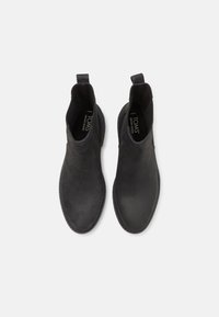 Botas de cuero negro hasta el tobillo con textura suave, paneles laterales elásticos y tiradores. Diseñadas para un uso fácil y un estilo minimalista.