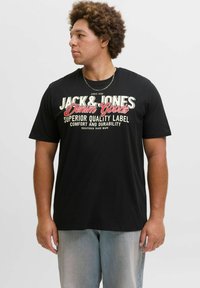Schwarzes Kurzarm-T-Shirt mit auffälligem weißen und roten grafischen Text, der auf der Vorderseite "JACK & JONES Denim Goods" lautet.