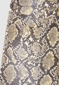 Schlangenleder-Optik Stoff mit strukturierter Oberfläche in Brauntönen und Beige. Enthält eine Taschendetail mit genähter Umrandung.