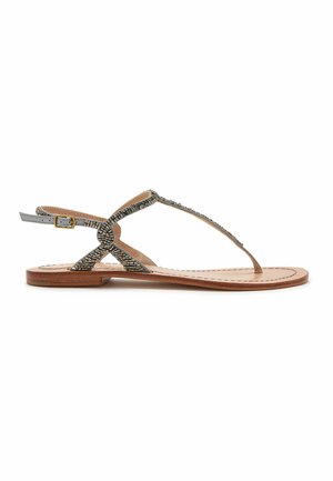 Sandalo basso in pelle con sottili cinturini metallici con perline, chiusura con fibbia alla caviglia e suola color cuoio con cuciture visibili.