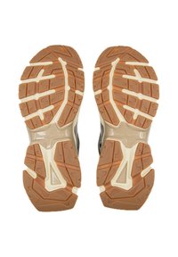 Sportschuhe mit strukturierten Gummisohlen, die eine Kombination aus Braun- und Cremetönen sowie markante Profilmuster für besseren Halt aufweisen.