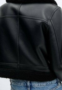 Giacca di pelle nera con design corto, caratterizzata da un collo in shearling morbido e una finitura testurizzata, con cuciture dettagliate sul retro.