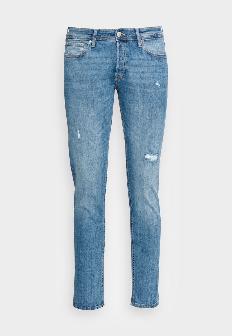 Jeans de ganga azul claro com um corte justo, apresentando remendos desgastados e um design clássico de cinco bolsos. O material parece suave e flexível.