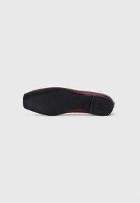 Burgundy leather flat shoe with a smooth finish and a rectangular black rubber sole, featuring subtle branding on the bottom.