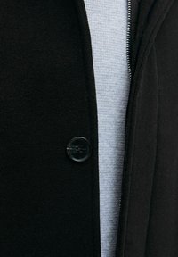 Must must jakk, millel on sile disain, nähtav must nupuga ning all olev tekstureeritud hall särk. Toodetud on ka tõmblukku.