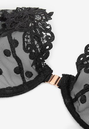 Czarna koronkowa biustonosz z przezroczystym siateczkowym wzorem, zdobiony kropkami, haftem kwiatowym oraz z różowo-złotym metalowym zapięciem z tyłu.